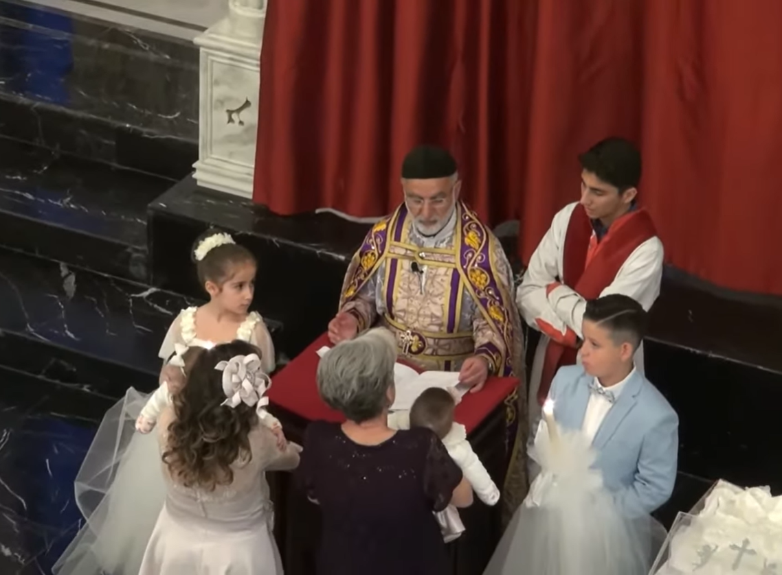 神父在教堂內為新生兒施洗。 （YouTube@Assyria TV影片截圖）